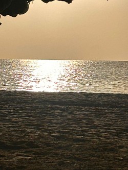 The glow of the setting sun casts a golden shadow over the sea's calm, smooth waves